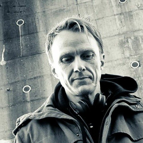 Schwarzweiß-Porträt von Michael Suding aka MIQUELE, mit Kopfhörern vor einer Betonwand